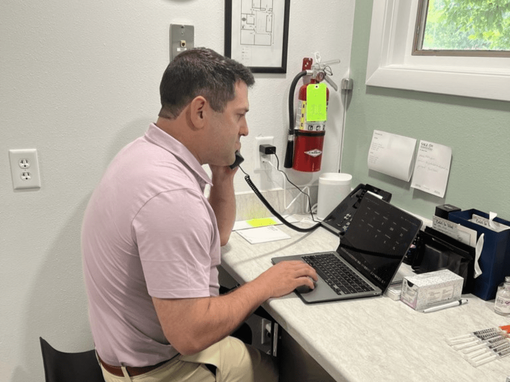 Person talking on the phone and working on laptop simultaneously